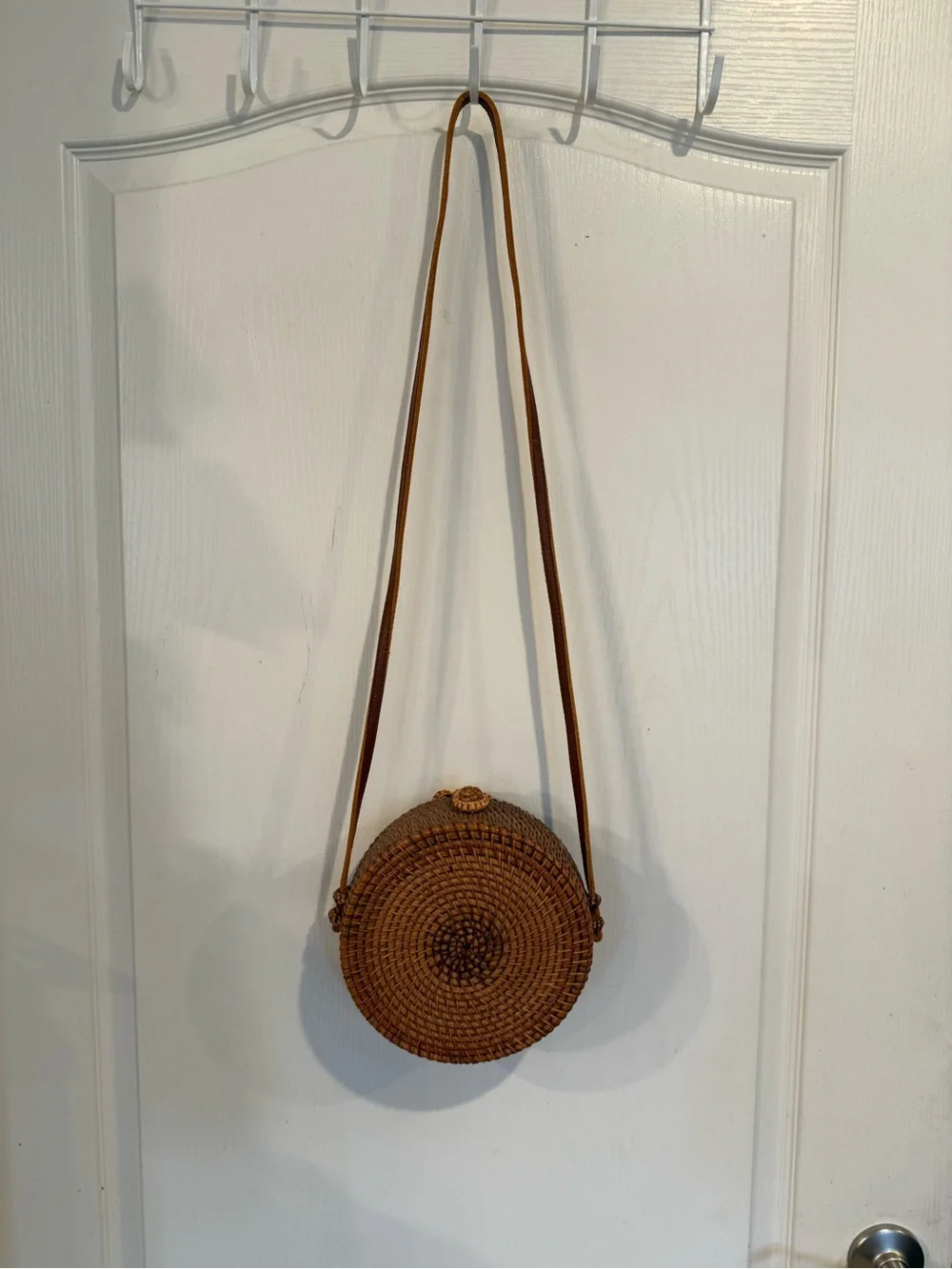 Tan, round, handwoven rattan crossbody bag